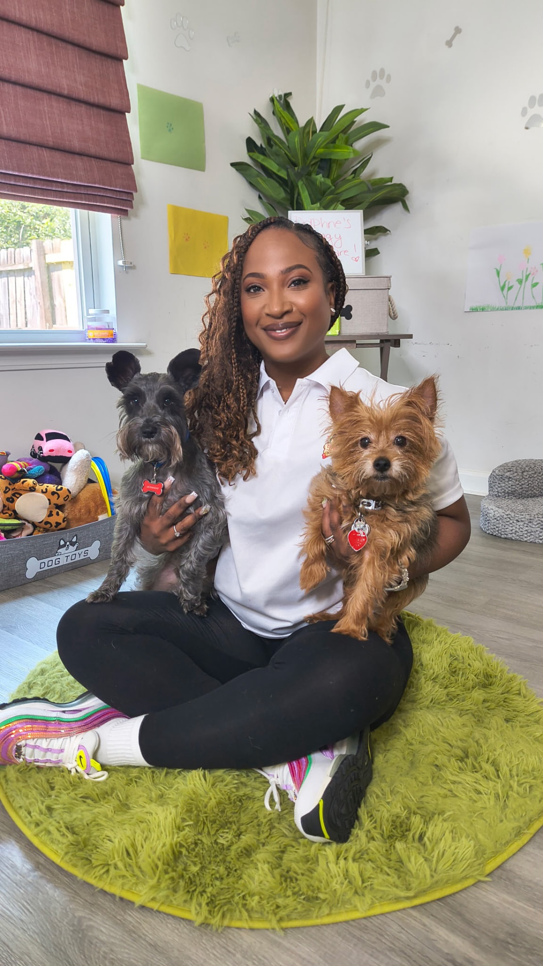 Daphne sitting on the playroom rug holding two small dogs